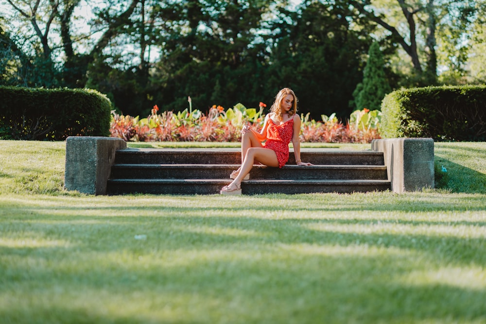 woman in red dress sitting on black wooden bench during daytime