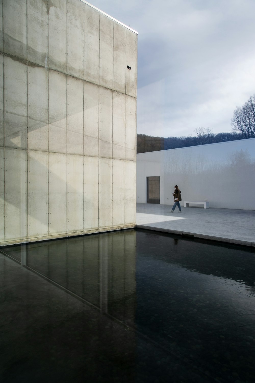 person in white shirt and black pants standing on gray concrete floor near white concrete building