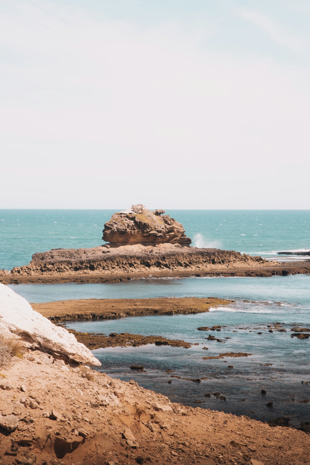 formação rochosa marrom no mar durante o dia