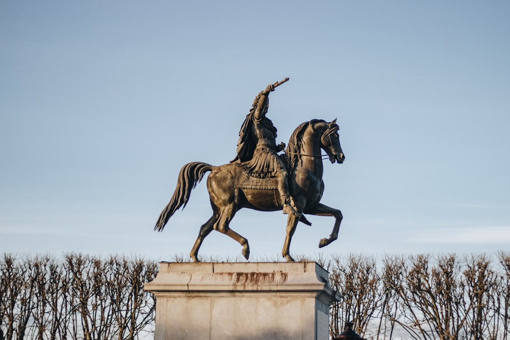 Statue de cheval brun sur une colonne de béton blanc pendant la journée