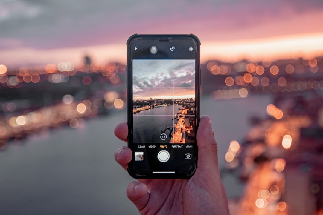 person holding black iphone 5 taking photo of city during sunset