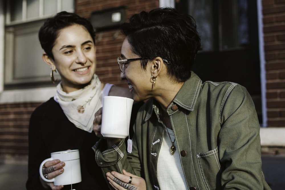 woman in brown jacket holding white ceramic mug