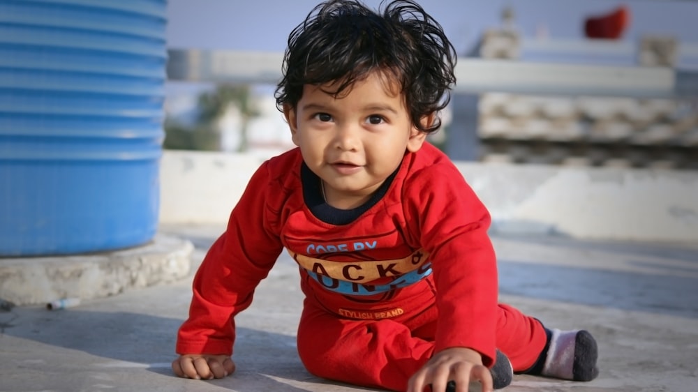 boy in red and blue sweater sitting on the floor