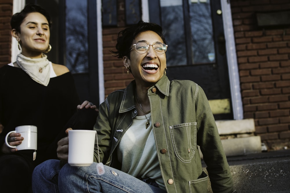 woman in green button up jacket holding white cup