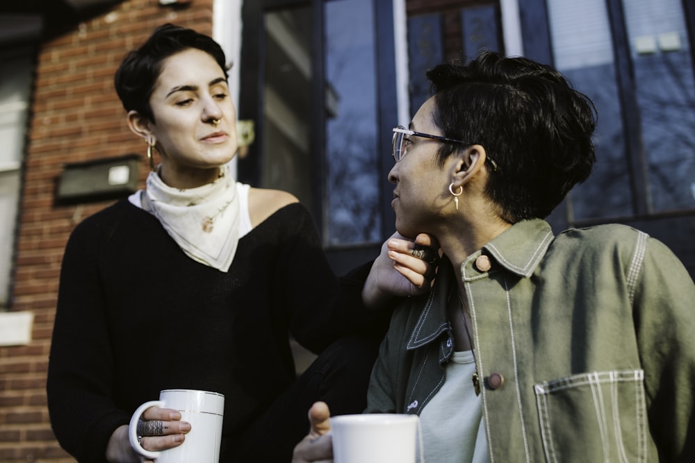 woman in green jacket holding white ceramic mug