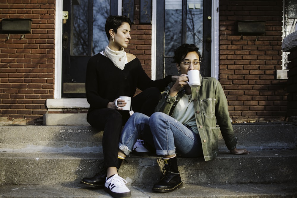 woman in black suit jacket sitting beside man in green jacket