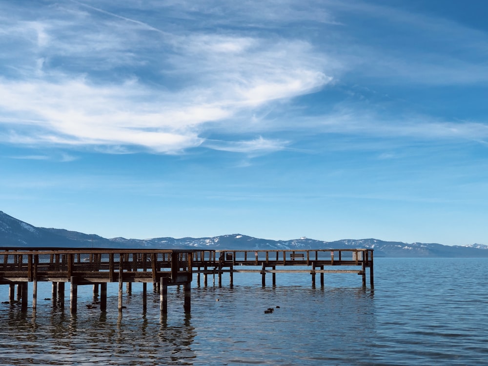 brown wooden dock on sea under blue sky during daytime