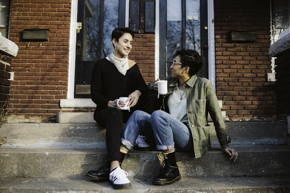 woman in black suit jacket sitting beside woman in green coat