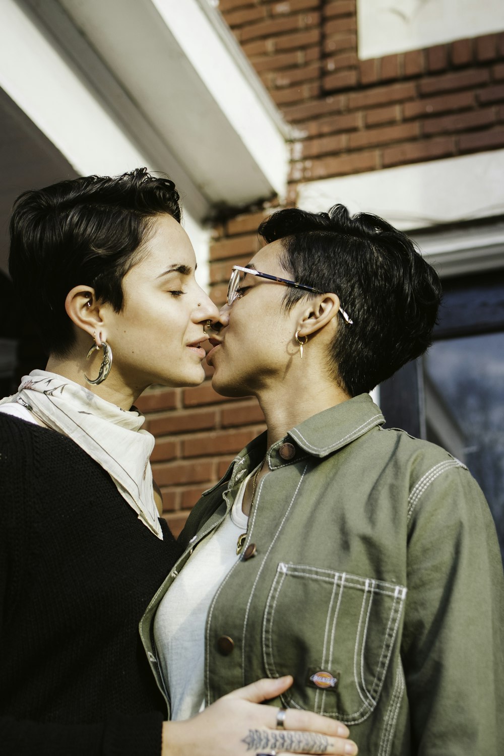 woman in green button up shirt kissing womans cheek