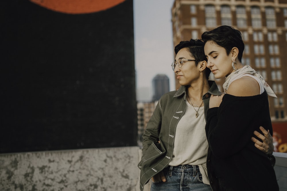 woman in brown jacket and blue denim jeans standing beside woman in black jacket