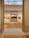 A well-lit art gallery features several framed paintings hung on beige walls. The focus is a large, prominent painting at the center, depicting a historical scene, possibly involving figures in a dramatic setting. The gallery has wooden floors and a high ceiling with spotlights.