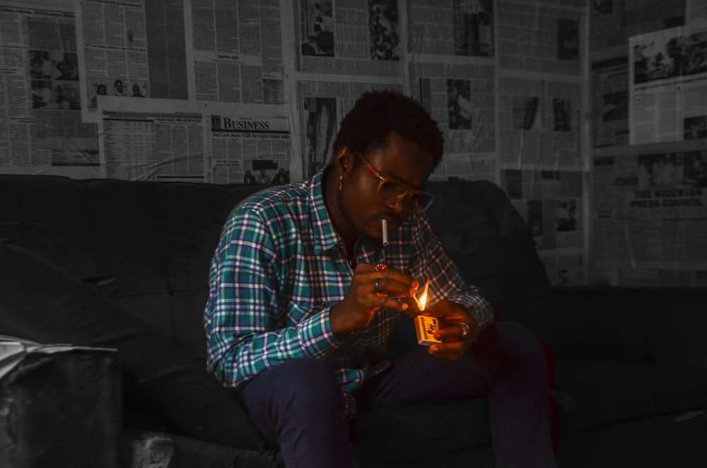 man in blue white and black plaid dress shirt holding lighted candle