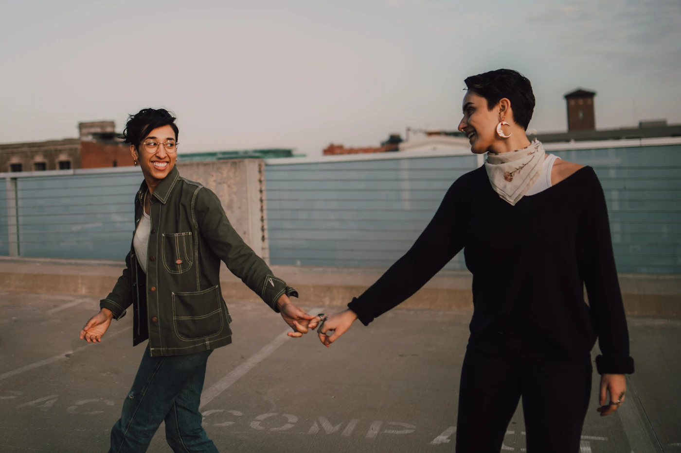 Jo and Marisol holding hands and laughing on a Brooklyn rooftop