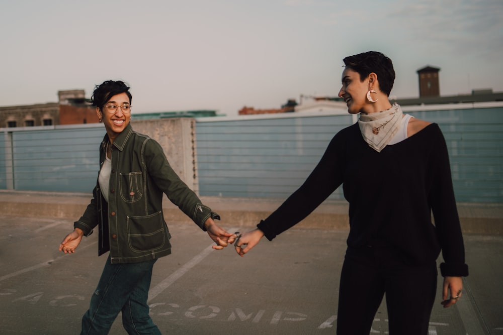 woman in black jacket and woman in gray jacket standing on gray concrete floor during daytime