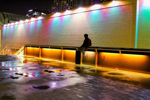 A lone figure standing beneath a neon-lit bridge with glitching lights.