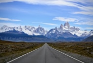gray concrete road near snow covered mountain during daytime