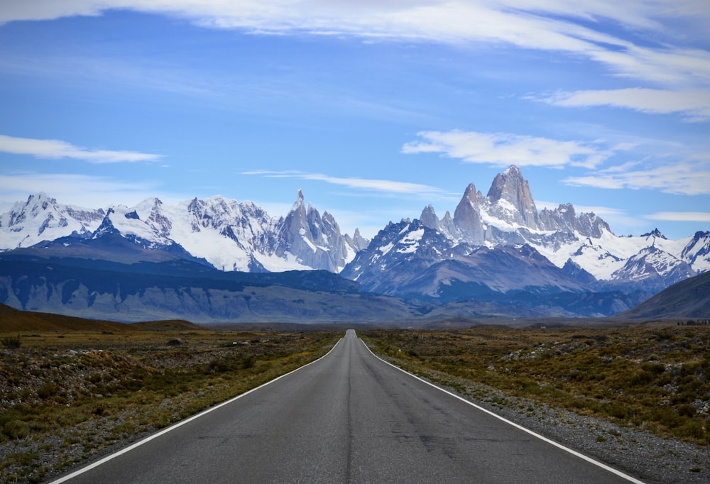 gray concrete road near snow covered mountain during daytime