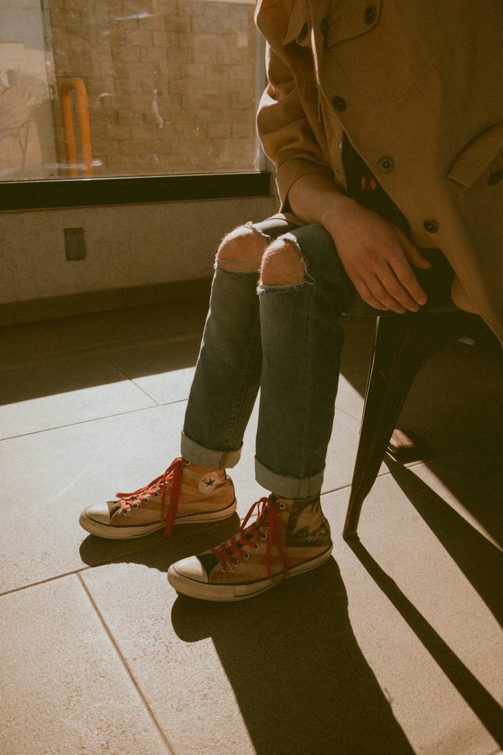 woman in brown coat and blue denim jeans sitting on chair