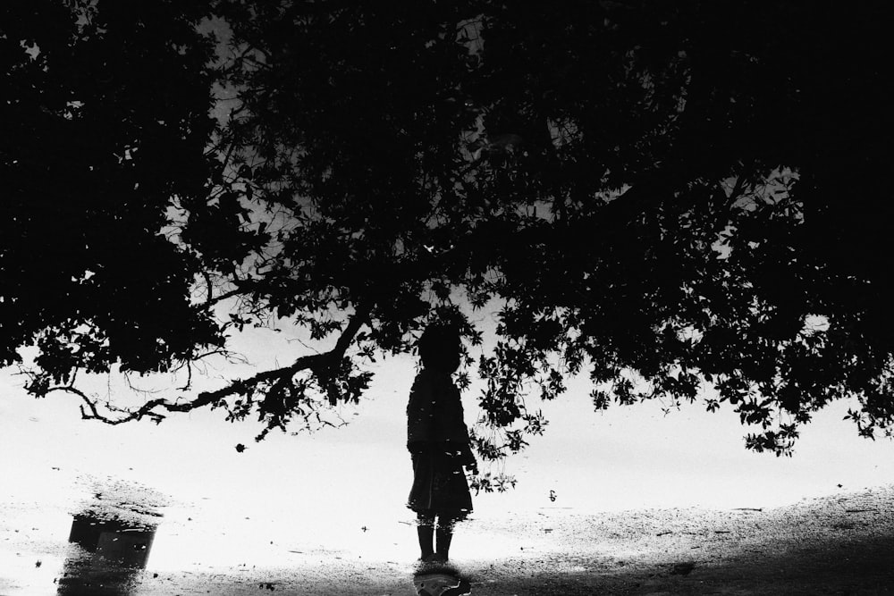 grayscale photo of man walking on beach