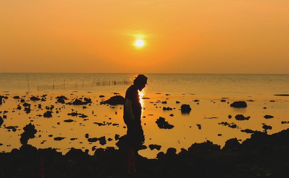 silhouette of woman walking on beach during sunset