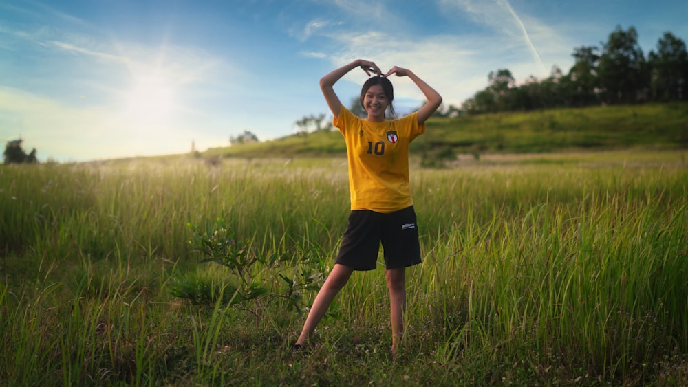 man in yellow crew neck t-shirt and black shorts standing on green grass field during