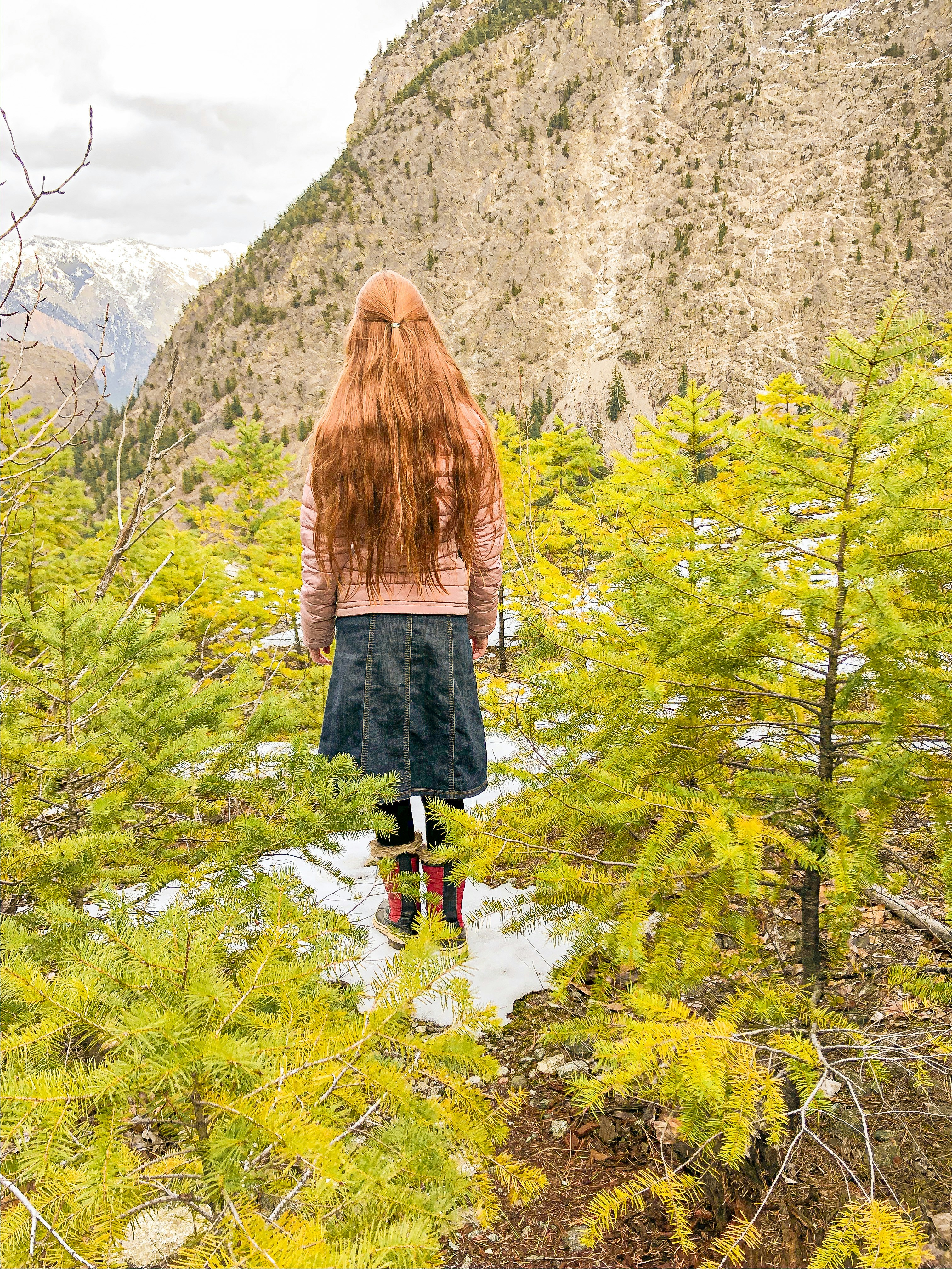 woman in brown sweater and black skirt standing on green grass during daytime