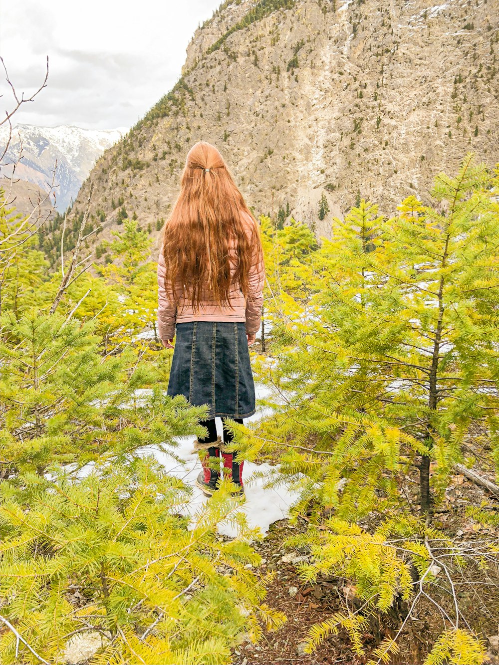 woman in brown sweater and black skirt standing on green grass during daytime