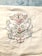 A detailed embroidery design featuring two symmetrical birds facing each other, surrounded by an intricate arrangement of floral and botanical patterns. The embroidery is colorful, with a variety of threads used to create a vibrant and elegant appearance. The background is a white fabric.
