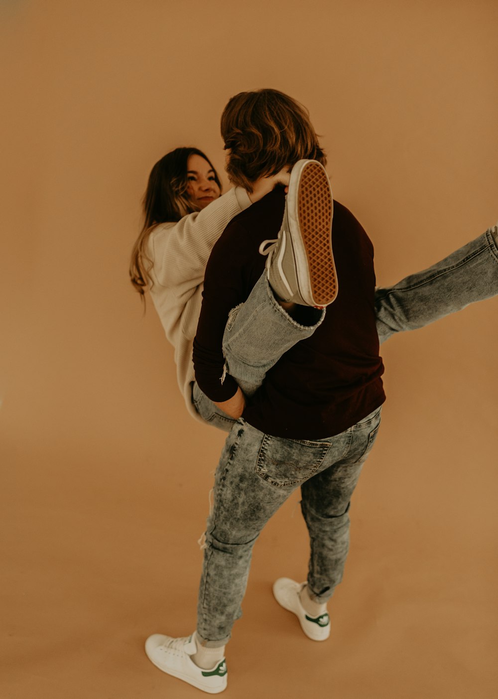 woman in white jacket and blue denim jeans hugging woman in black and white striped long