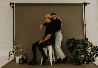 woman in black shirt and gray denim jeans sitting on white chair