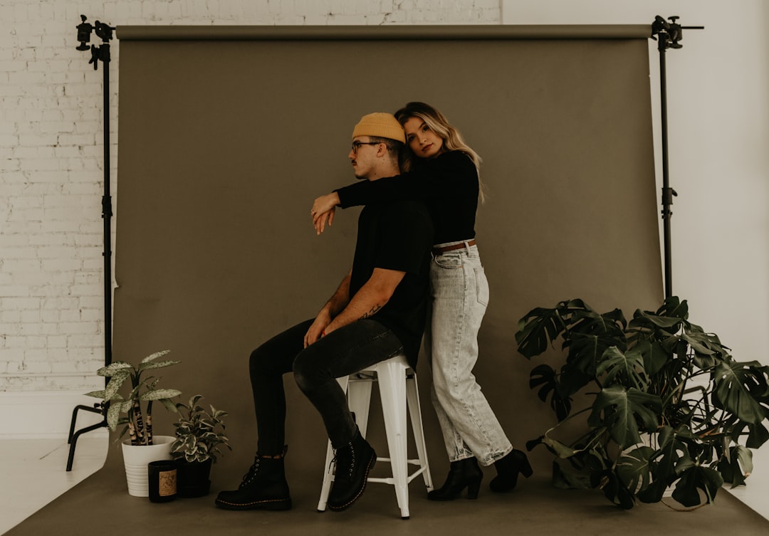 woman in black shirt and gray denim jeans sitting on white chair