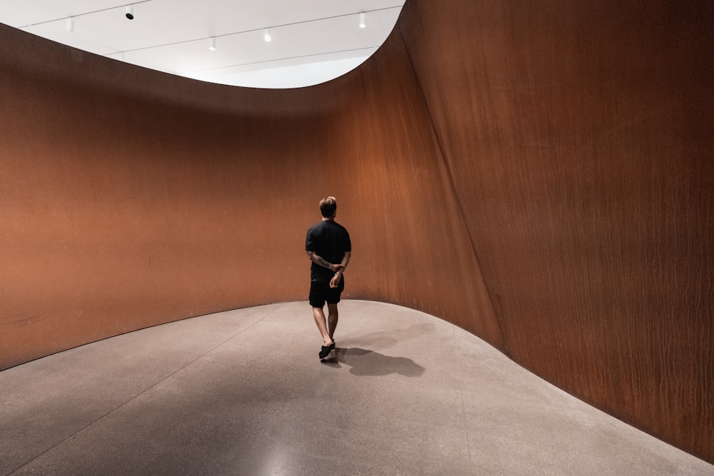 man in black jacket and black pants walking on brown wooden floor