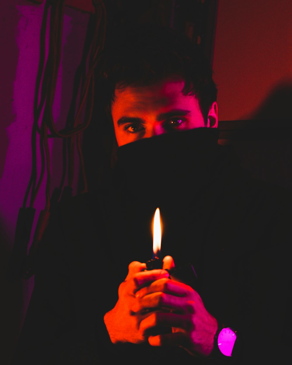 man in black hoodie holding lighted candle