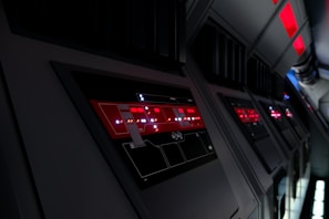 Painel de controle futurista com interface digital e luzes vermelhas em ambiente tecnológico escuro.
