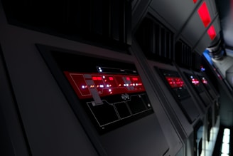 Painel de controle futurista com interface digital e luzes vermelhas em ambiente tecnológico escuro.