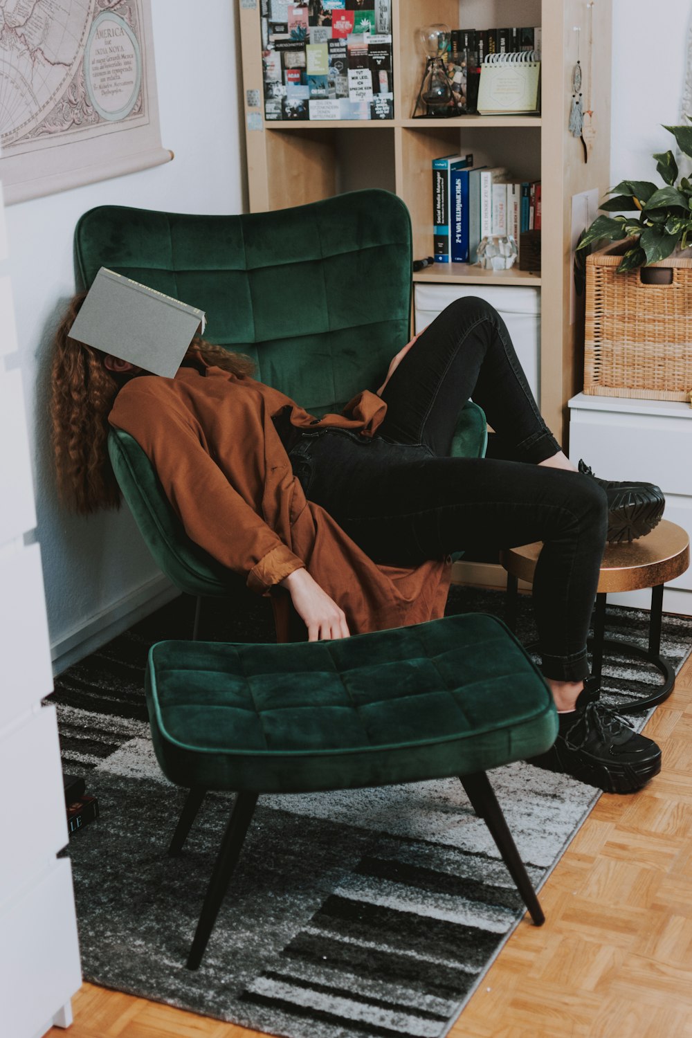 woman in red jacket and black pants sitting on green sofa chair