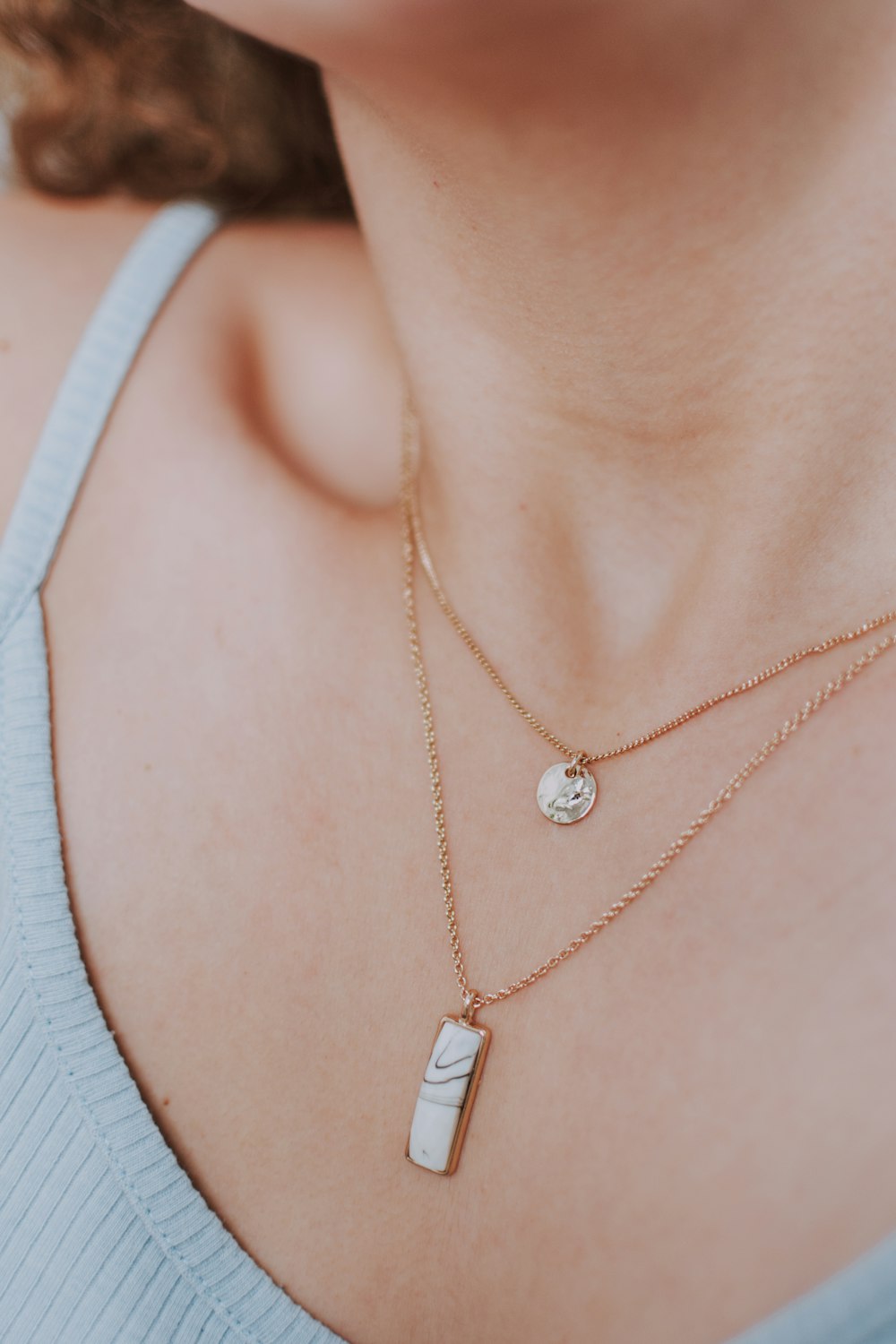 woman wearing gold necklace with silver pendant