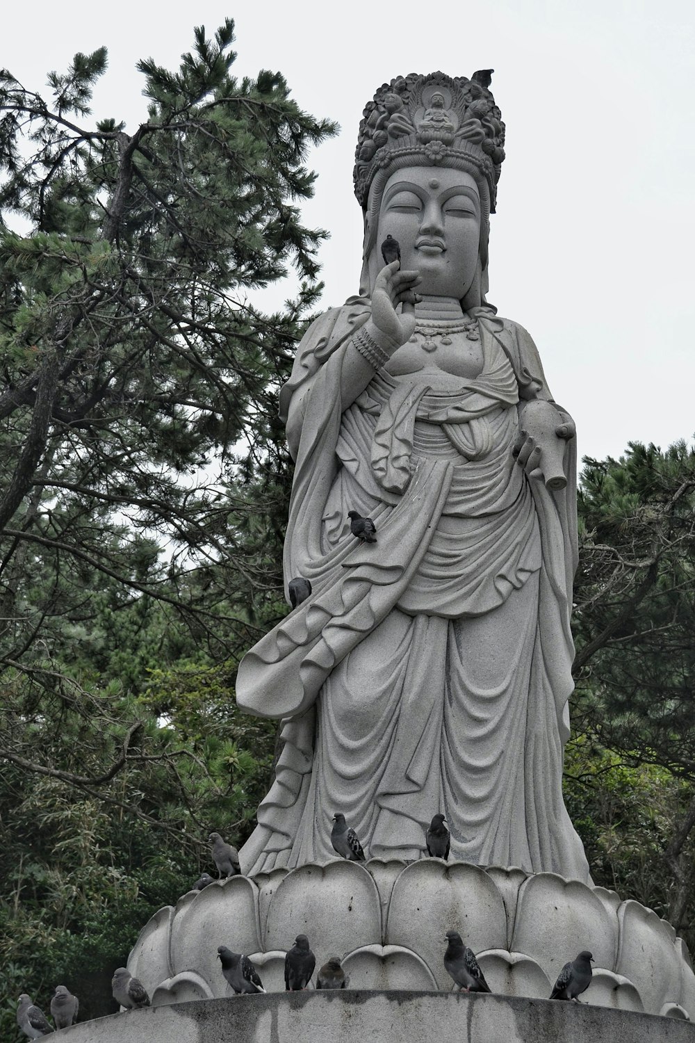 gray concrete statue near green trees during daytime