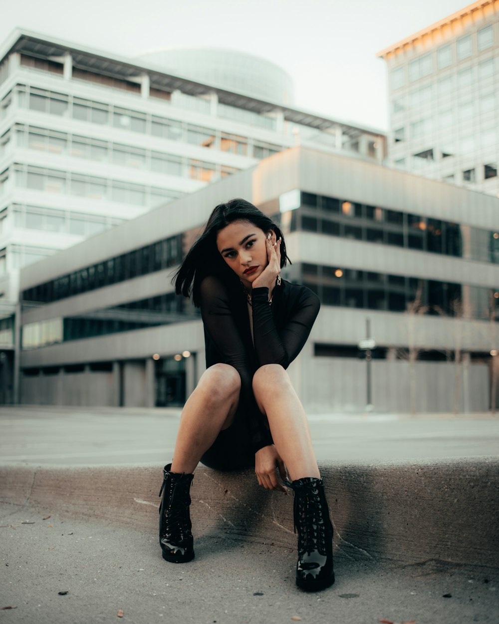 woman in black long sleeve shirt and black pants sitting on concrete floor