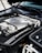 The image features the engine bay of a high-performance vehicle, showcasing a clean and well-maintained engine. Prominent branding includes an AMG logo on the engine cover, suggesting it is a Mercedes-AMG engine. The metallic components are arranged neatly, with visible pipes, wires, and textured areas.