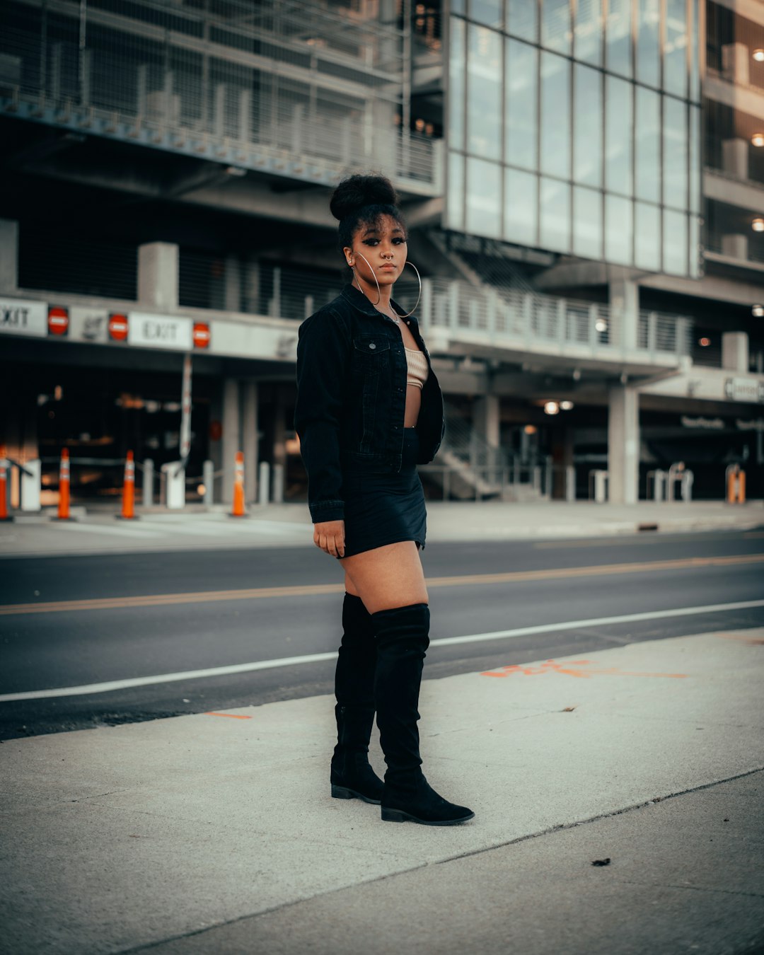 woman in black jacket and orange denim shorts standing on road during daytime