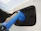 Close-up of a sleek EV charger mounted on a residential wall with a car plugged in.