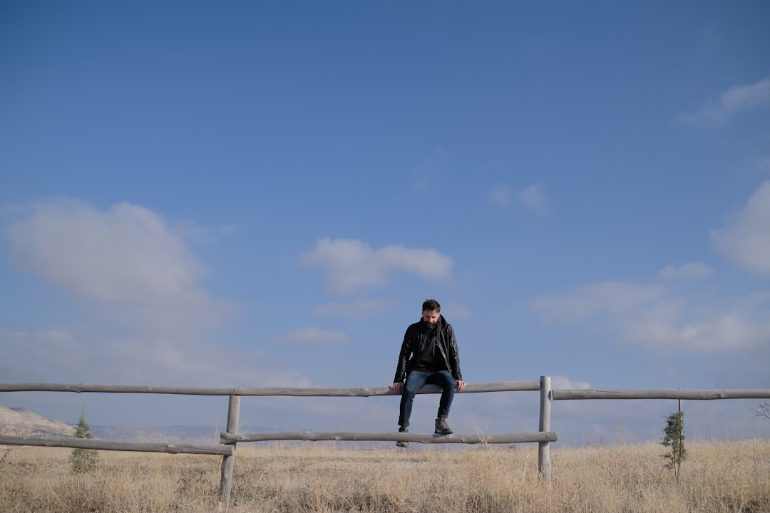 man in black jacket standing on brown field during daytime