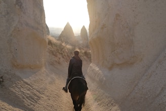 A horseback rider enjoying a peaceful ride through the scenic Red Valley with dramatic rock formations.