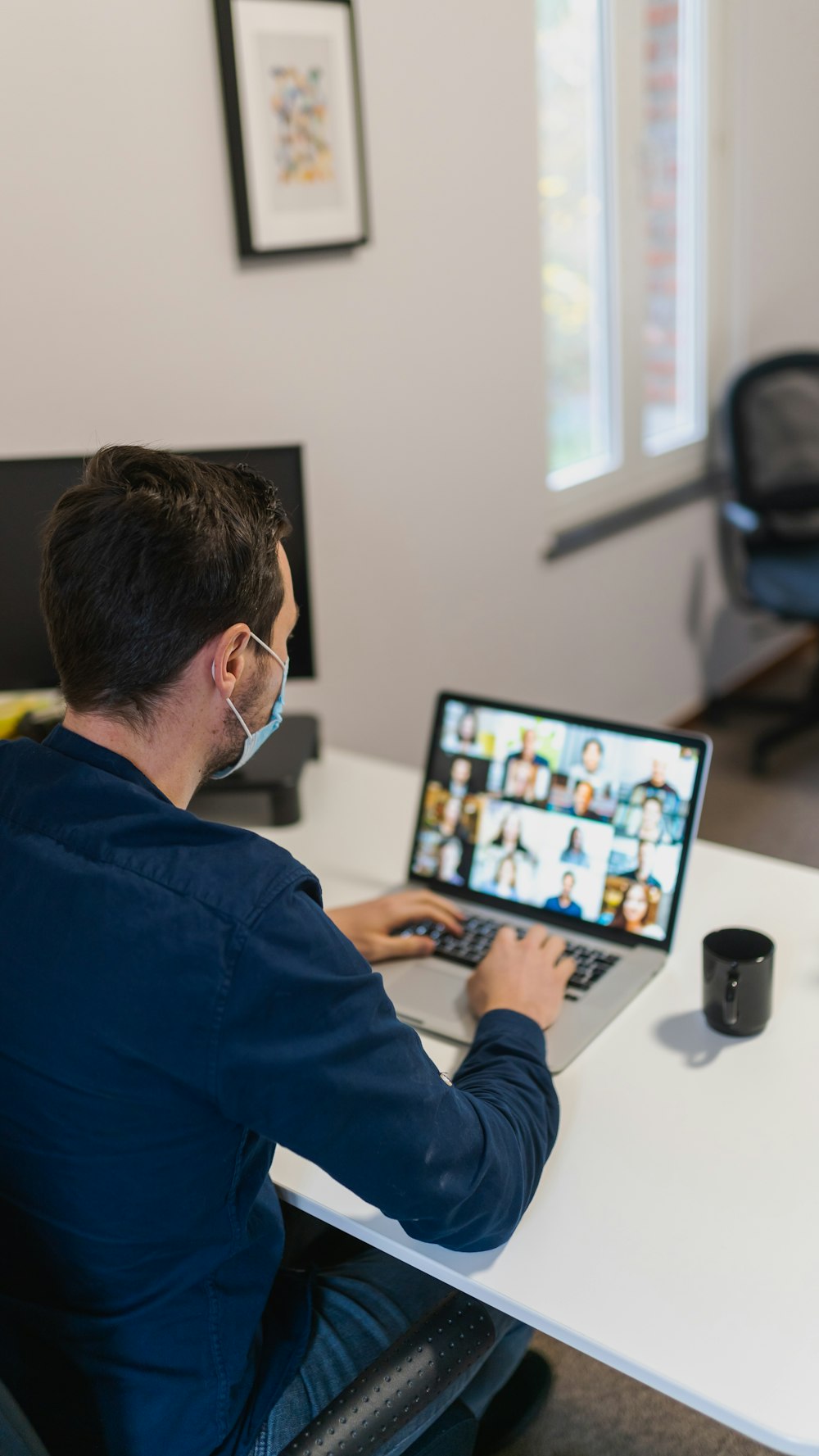 uomo in camicia blu a maniche lunghe utilizzando il computer portatile nero