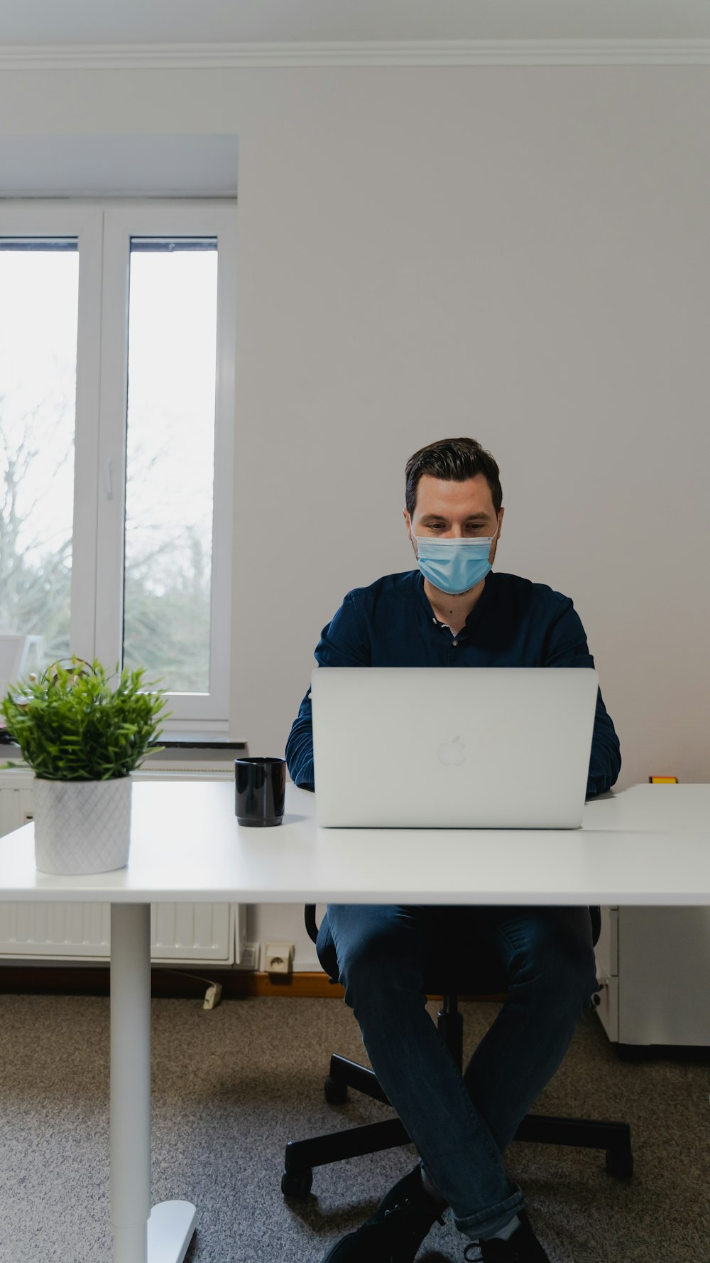 man in blue dress shirt using silver macbook