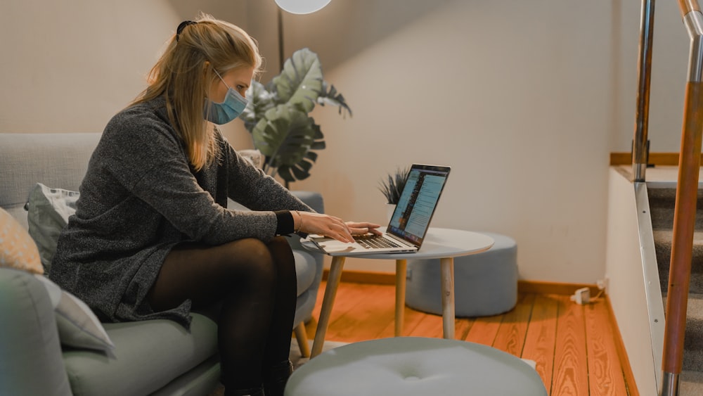 woman in gray sweater using macbook air