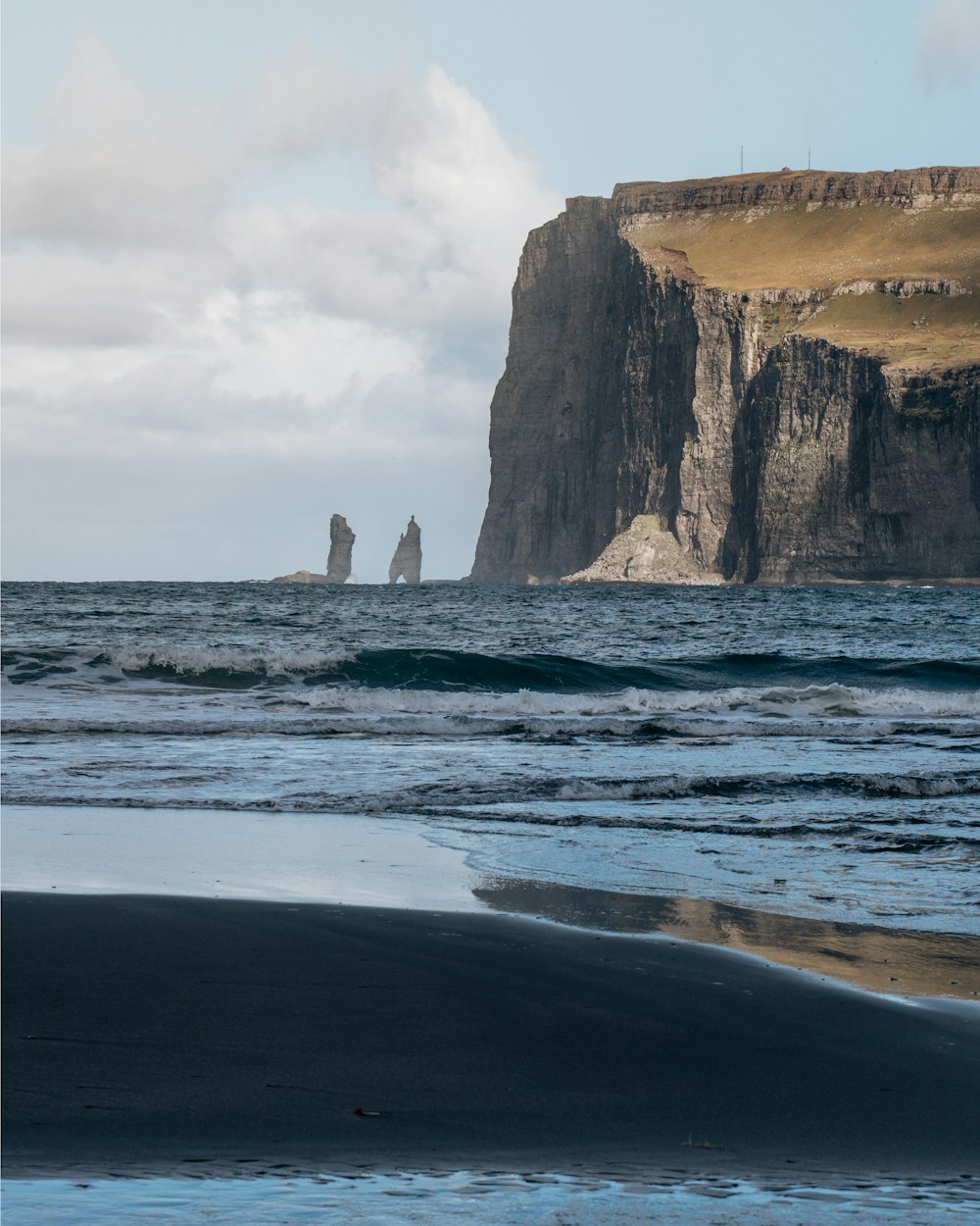 brown rock formation on sea under white clouds during daytime