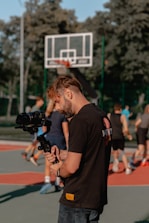 man in black crew neck t-shirt holding black dslr camera