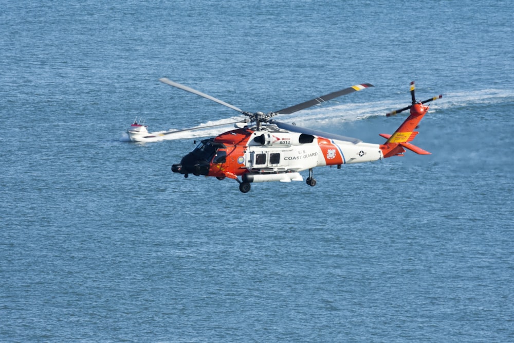 2 person riding orange and white boat on blue sea during daytime